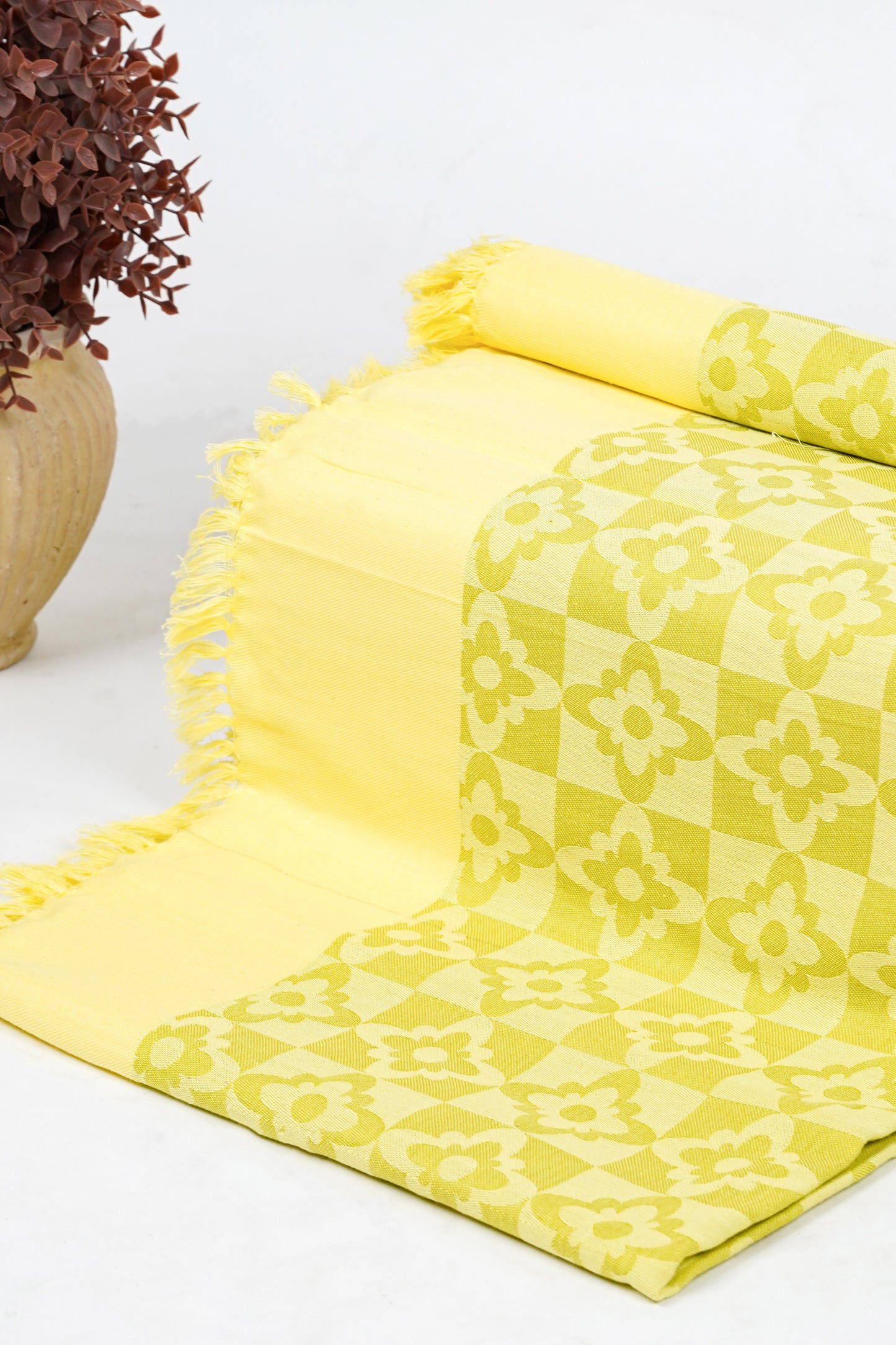 Yellow patterned towel with fringes on a white surface