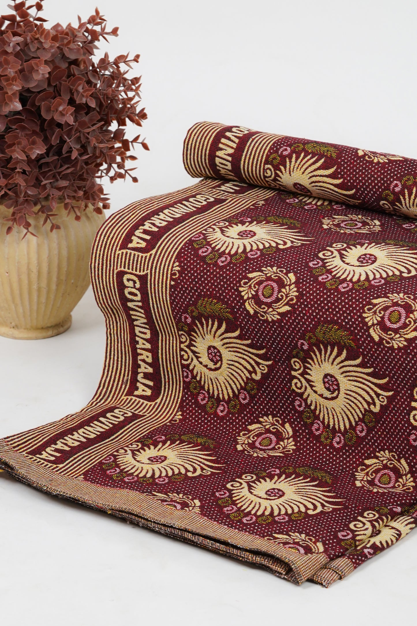 Maroon fabric with gold patterns and text on a background