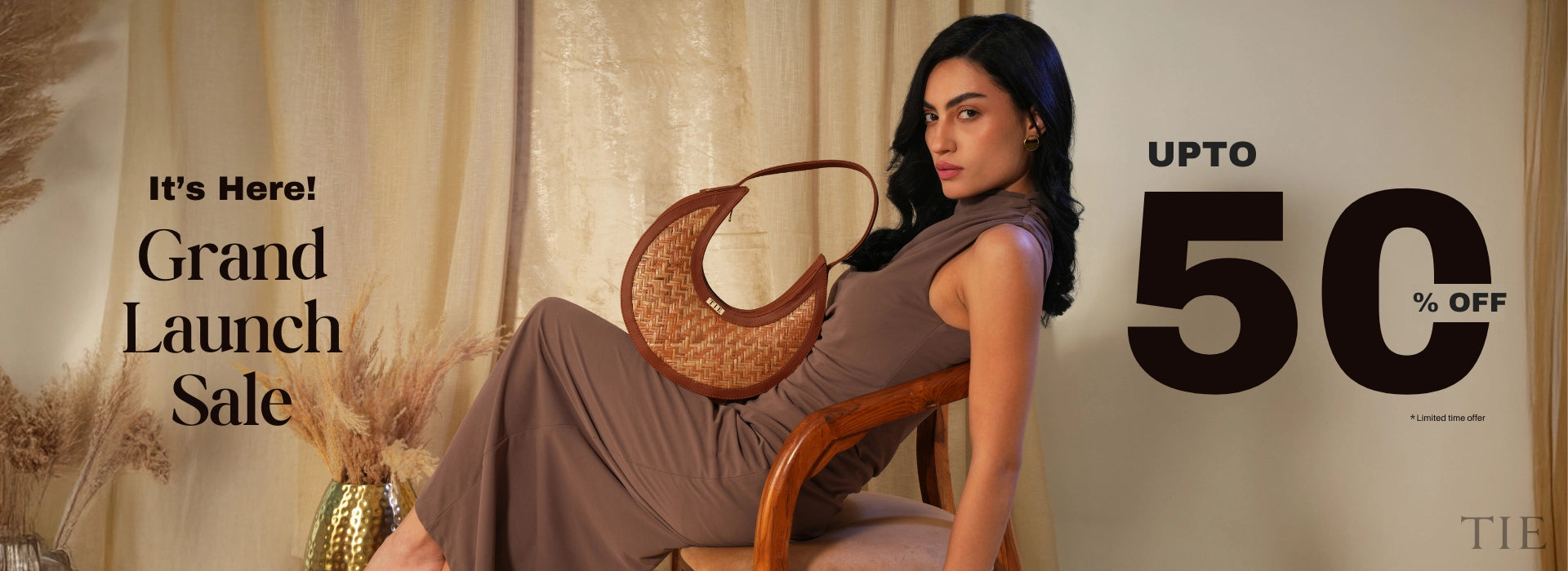 Woman holding a handbag with promotional text for a grand launch sale on a beige background
