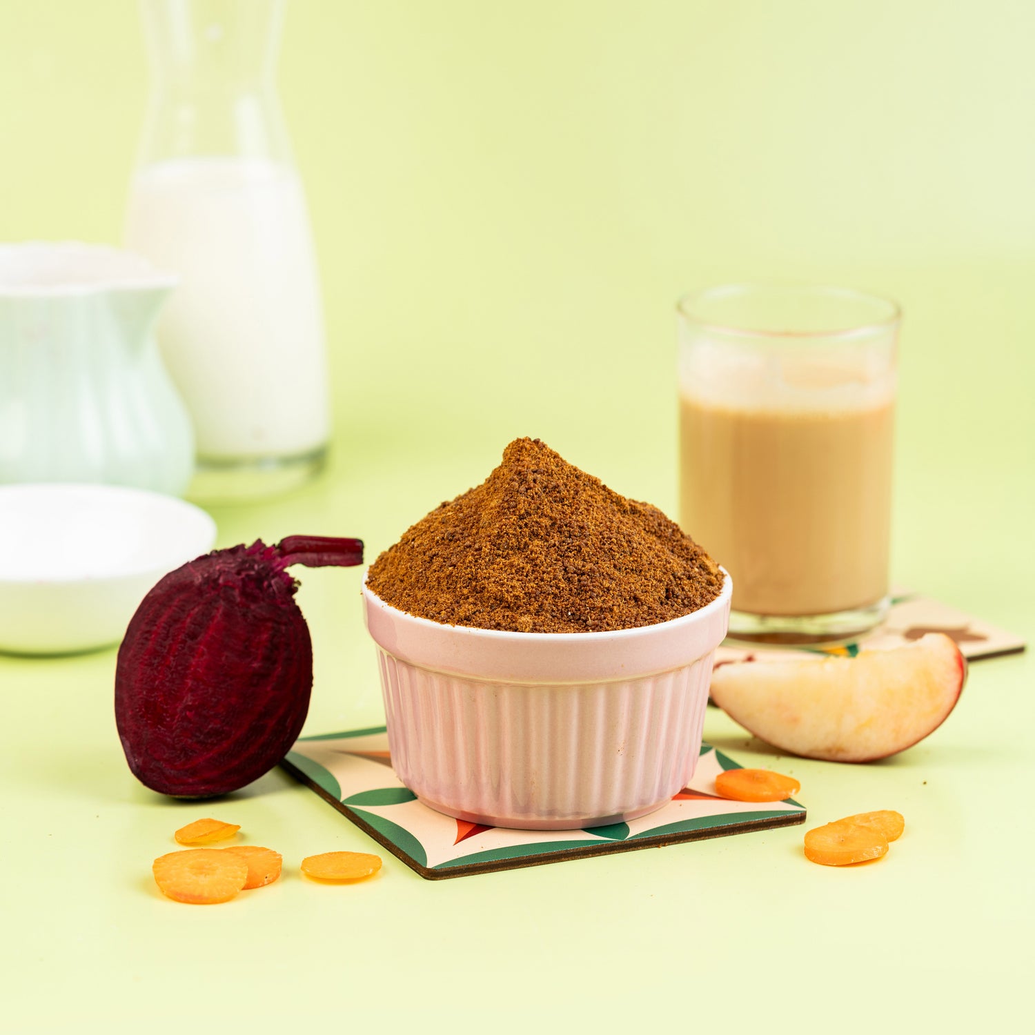 A pink mixing bowl with brown sugar, a glass of milk, and sliced apple on a green mat, with a bottle of milk in the background.