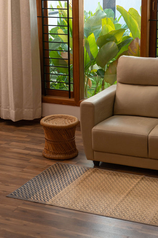 Beige sofa in a room with a window, plants, and a woven stool.