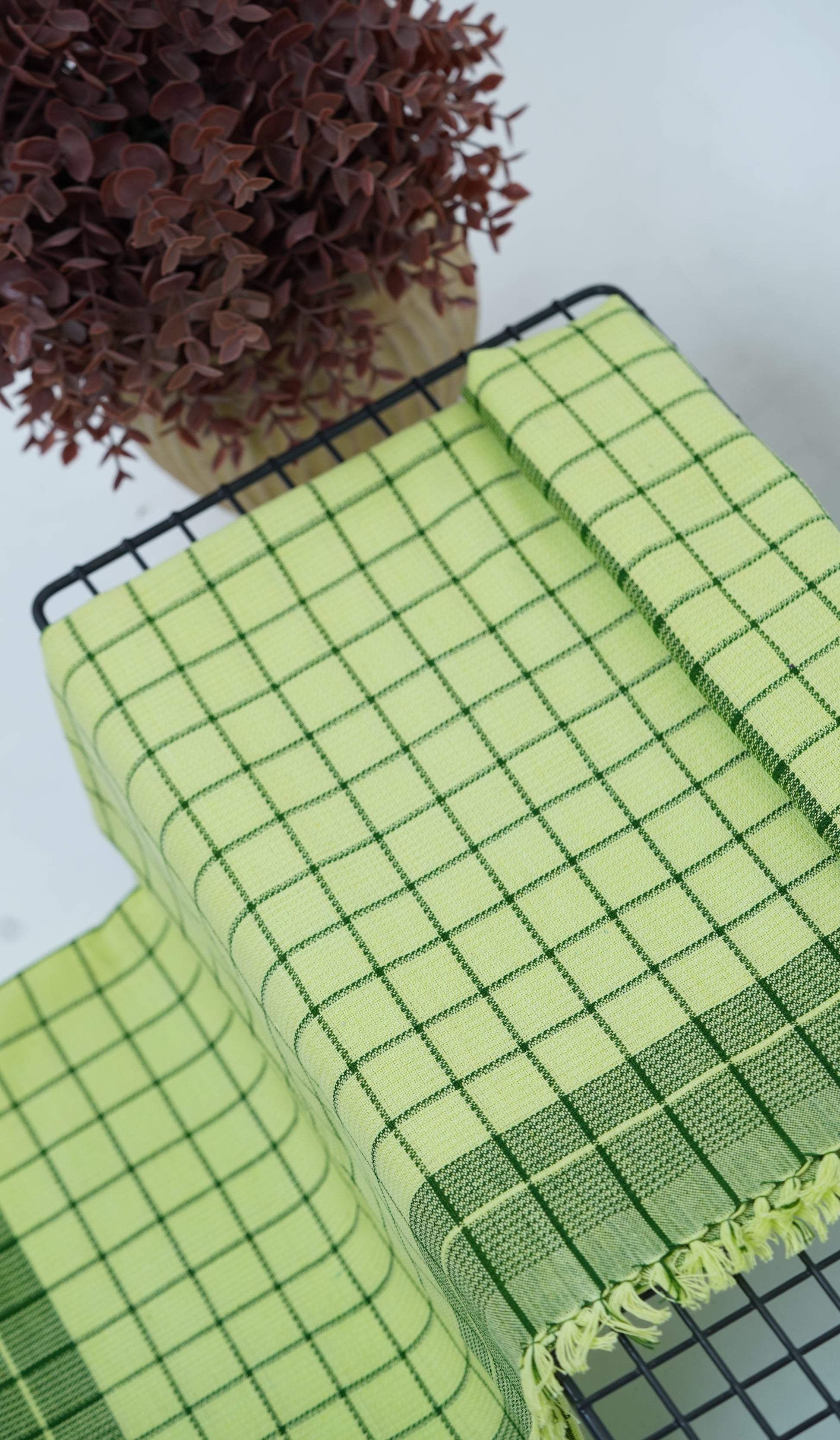 Chennimalai Soft Grid Weave Towel Lime Green on a table with a plant in the background