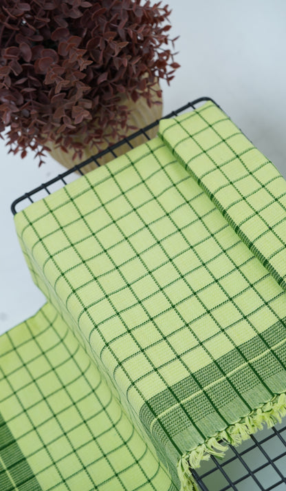 Chennimalai Soft Grid Weave Towel Lime Green on a table with a plant in the background