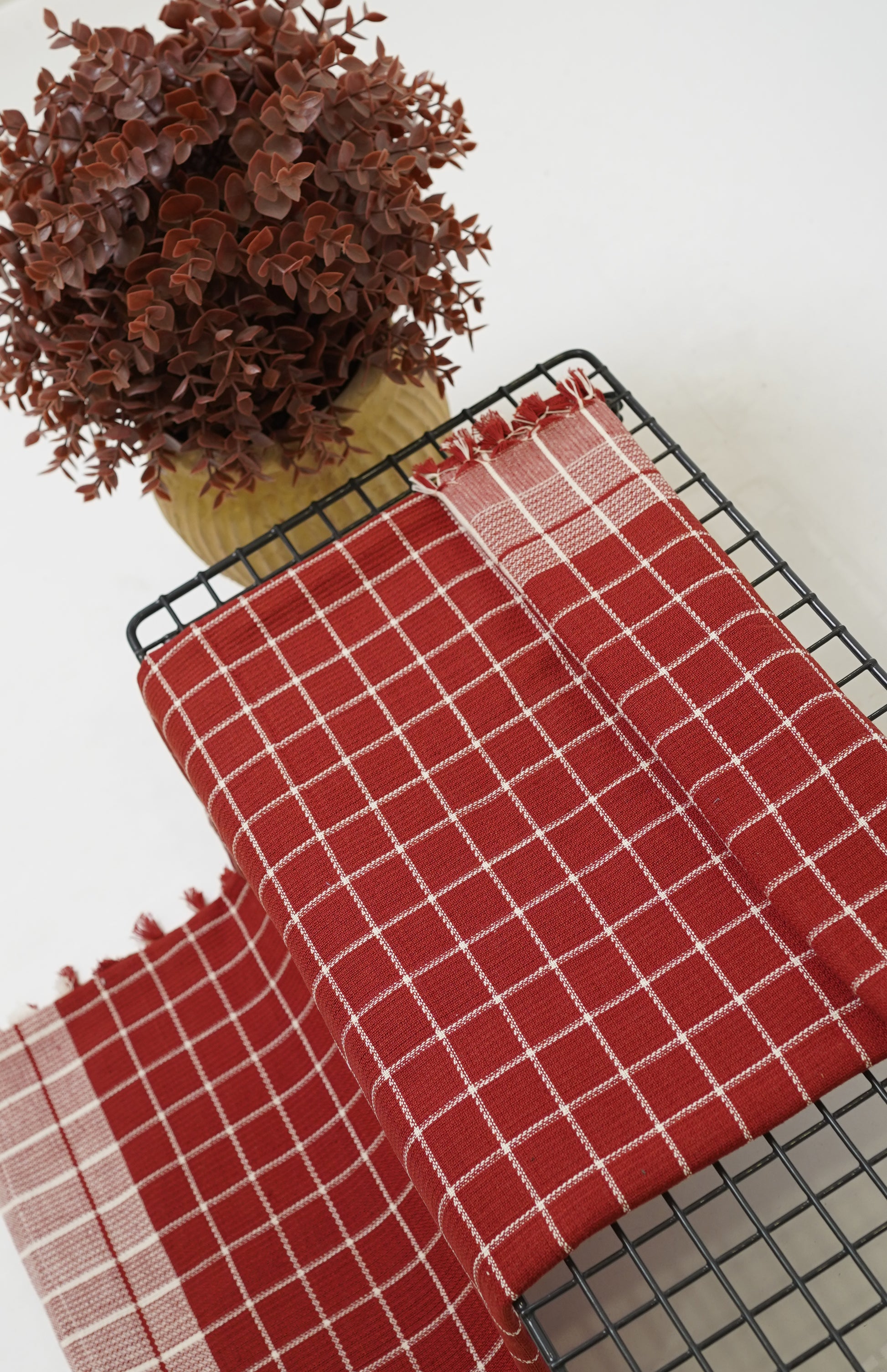 Red checkered Chennimalai Soft Grid Weave Towel on a black table with a white background