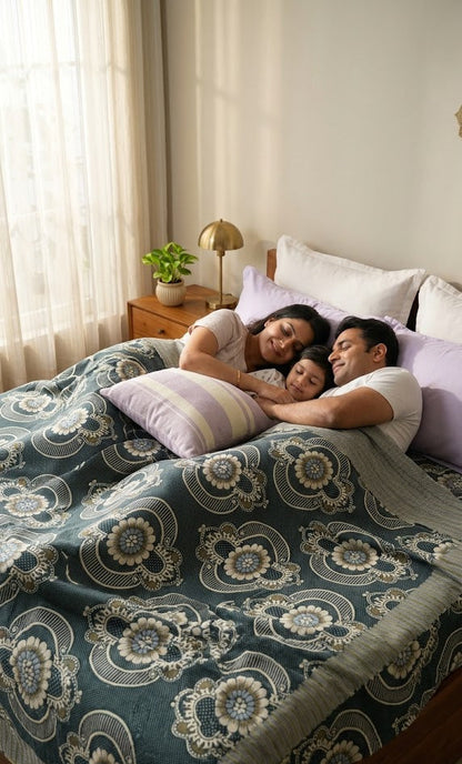 Family of three lying on a bed with a Jacquard Double Cot Bedsheet (Olive floral)