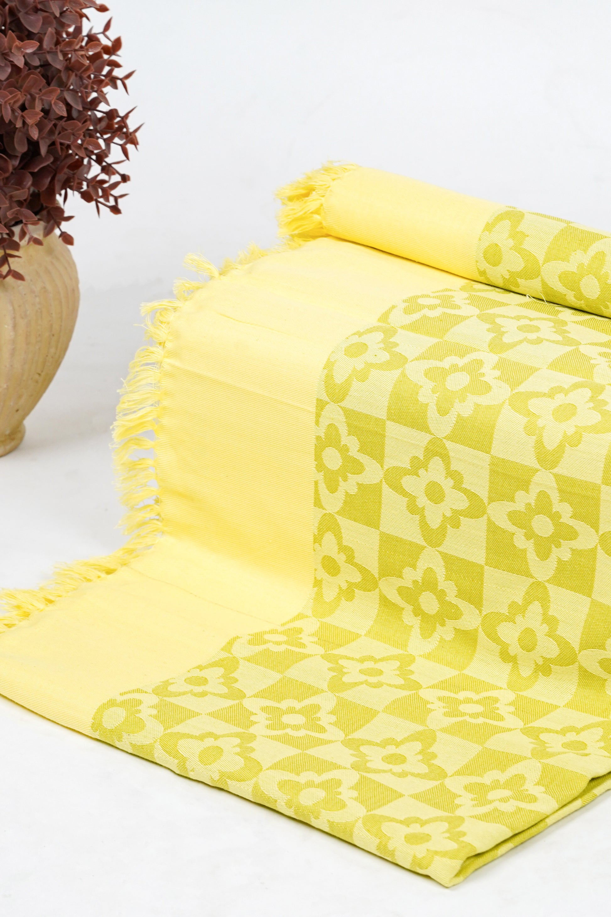 Yellow patterned towel with fringes on a white surface