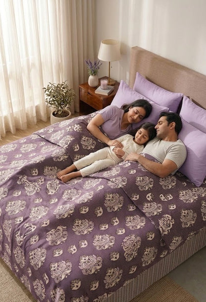 Family lying on a bed with a Jacquard Double Cot Bedsheet (Temple art Maroon)
