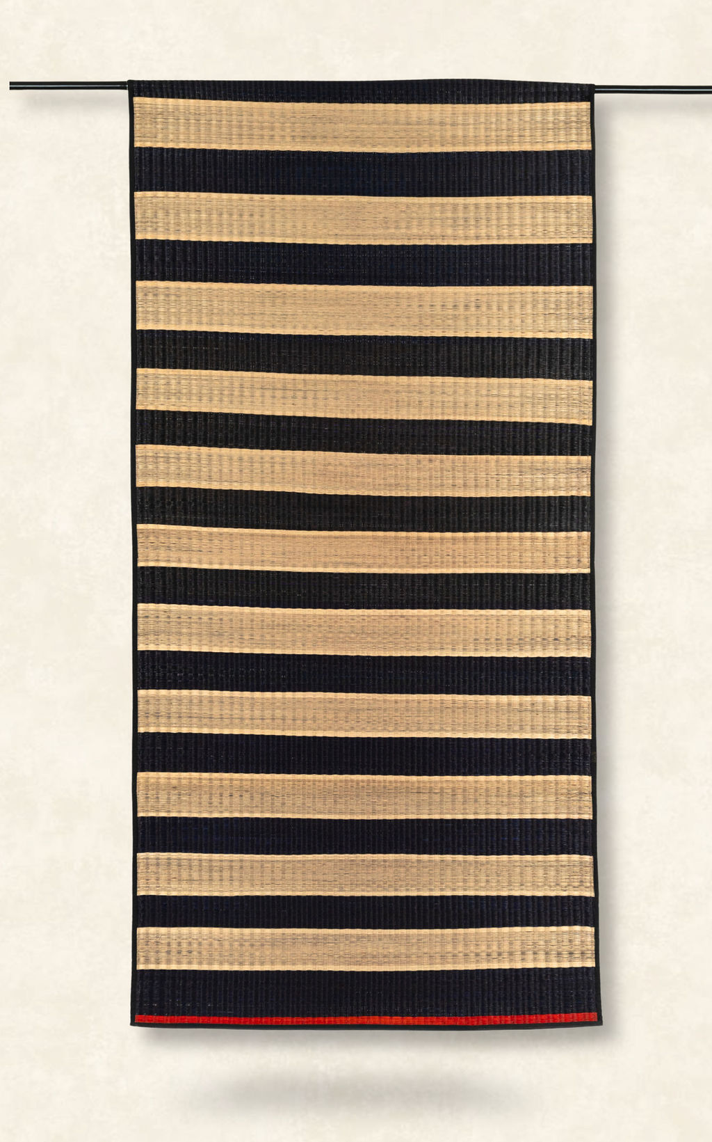 Striped rug with black and beige stripes on a white background