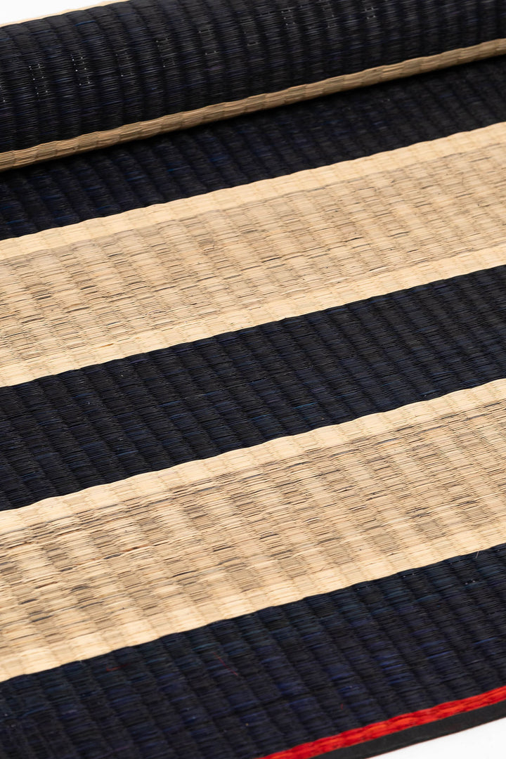 Close-up of black and beige striped fabric with a red line.