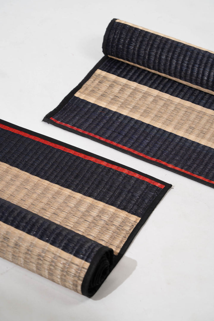 Two rolled-up mats with black and beige stripes on a white background