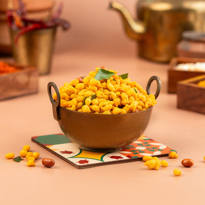 A bowl of kaara boondhi, also known as crispy gram flour balls, presented on a table with a patterned napkin underneath.