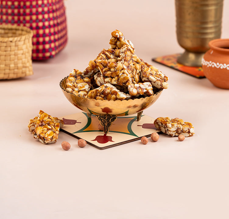 A bowl of Kovilpatti Kadalai (peanut candy) placed on a colorful placemat, with candy pieces scattered around and a woven basket in the background.