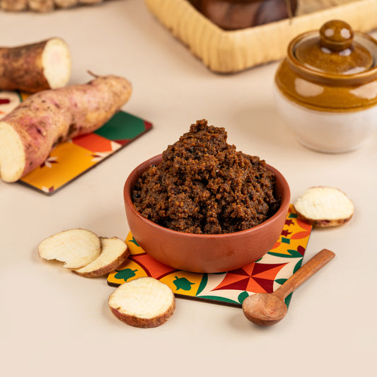 A bowl of Magaani Kizhangu Thokku with slices of cassava on the side, served on a colorful mat.