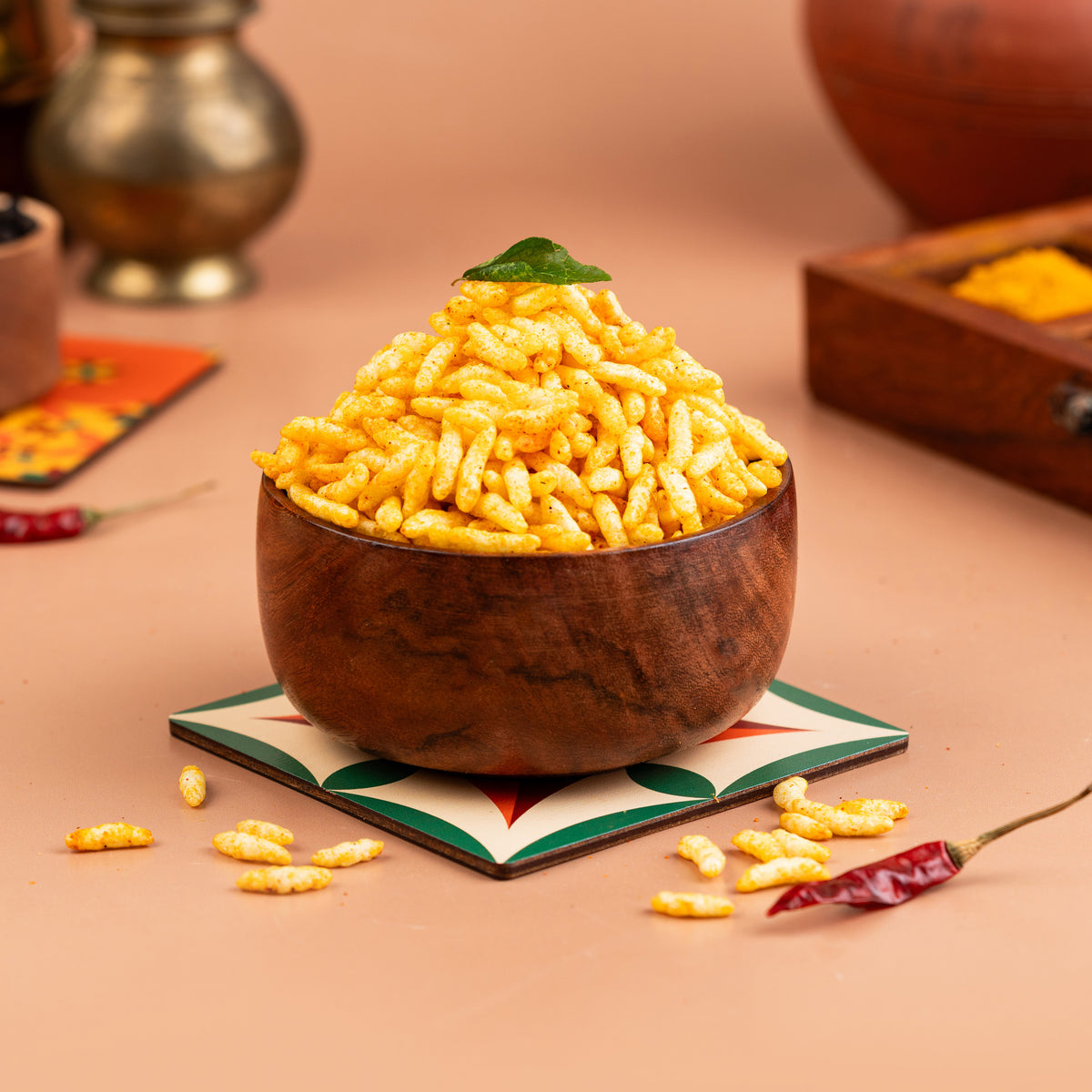A wooden bowl filled with yellow masala puffed rice, placed on a colorful coaster with a decorative background.