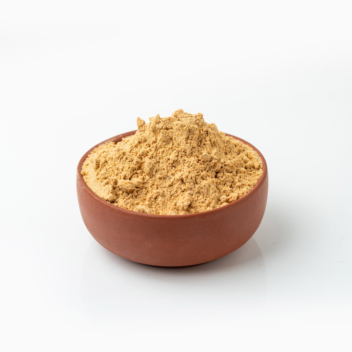 Brown Murungai Podi (Moringa Powder) in a terracotta bowl on a white background