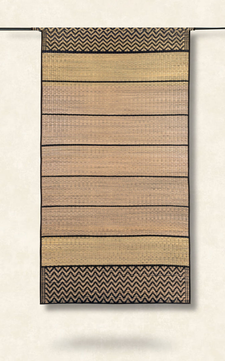 Woven grass mat with striped pattern on a plain background