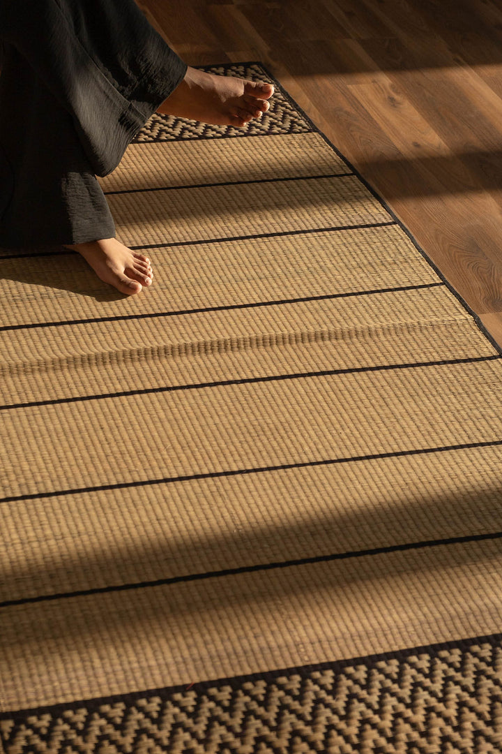 Person sitting on a grass mat floor in a traditional room.