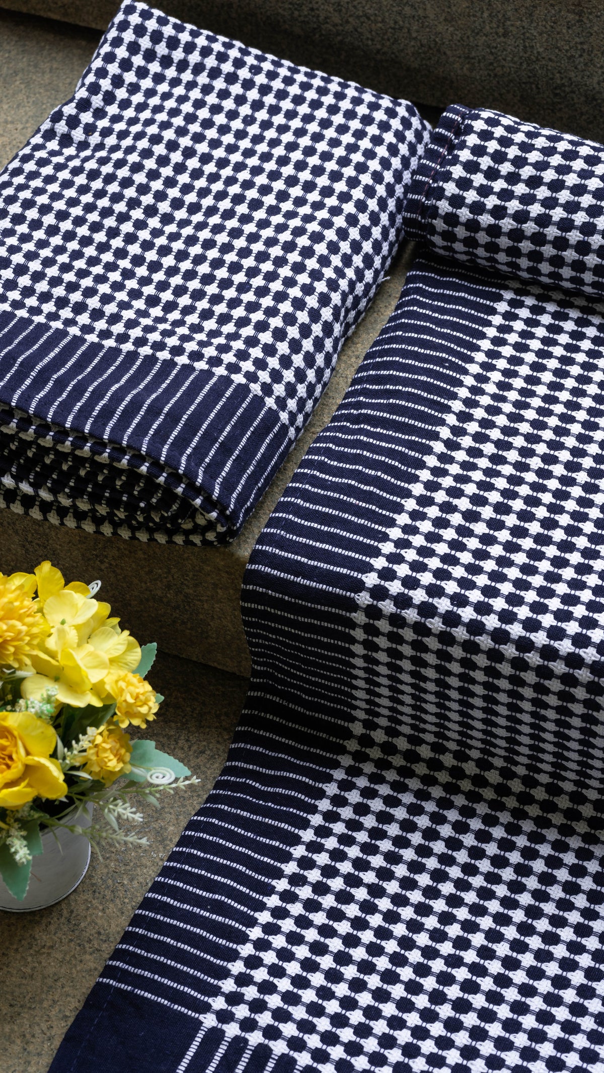 Navy and white checkered fabric on a surface with yellow flowers in the background