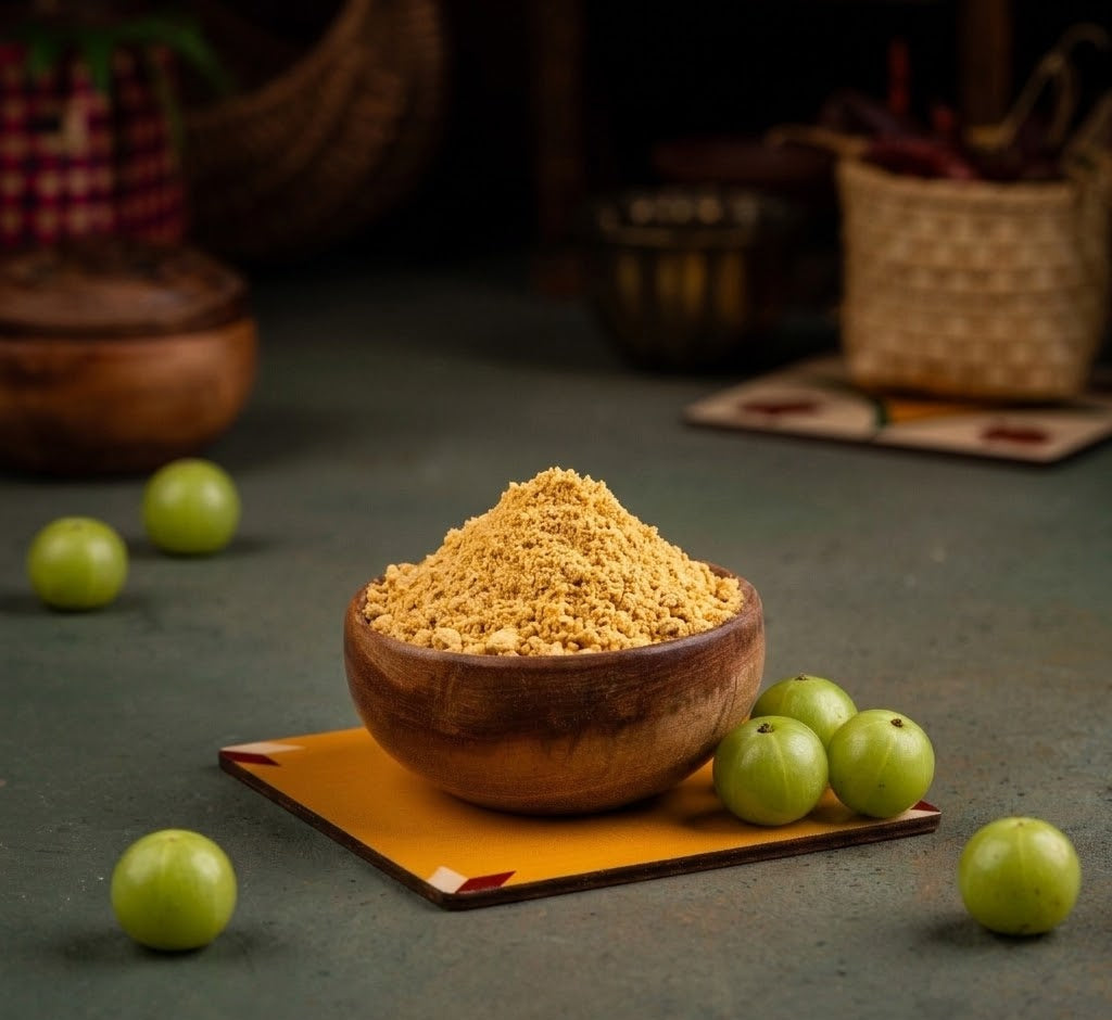 Wooden bowl filled with Nellikai Podi on a dark surface with Amla fruits around
