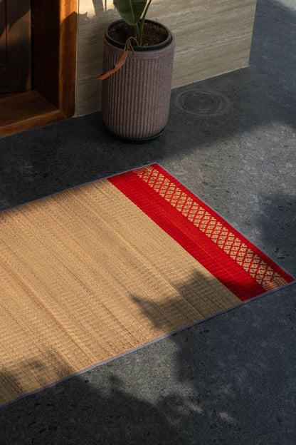 Textured grass mat with beige and red pattern on a dark floor.