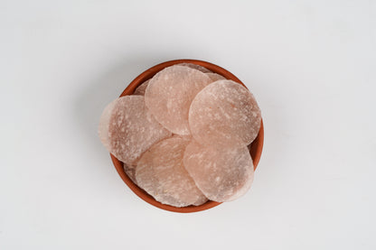 Terracotta bowl filled with round, beige-colored stones on a light gray background