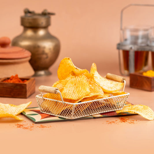 A basket of crispy potato wafers with a spicy seasoning, presented on a table with a warm background.