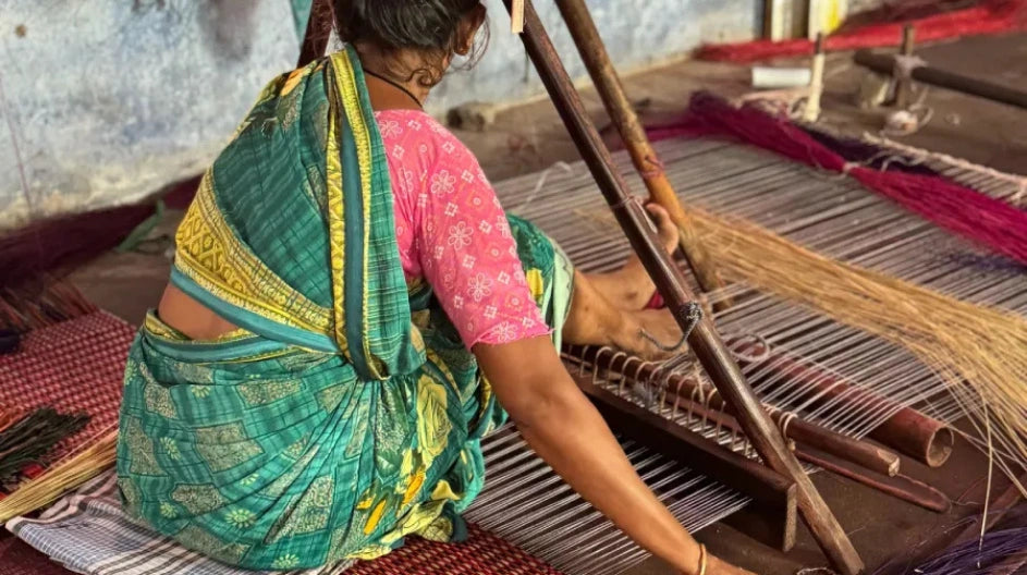 Woman weaving on a traditional loom in a workshop setting.