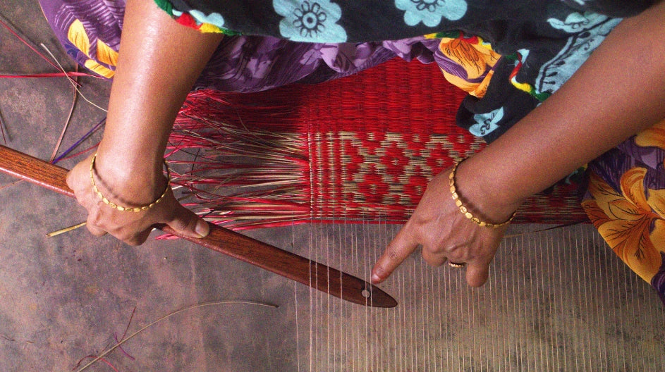 Person weaving with a red basket on a textured surface