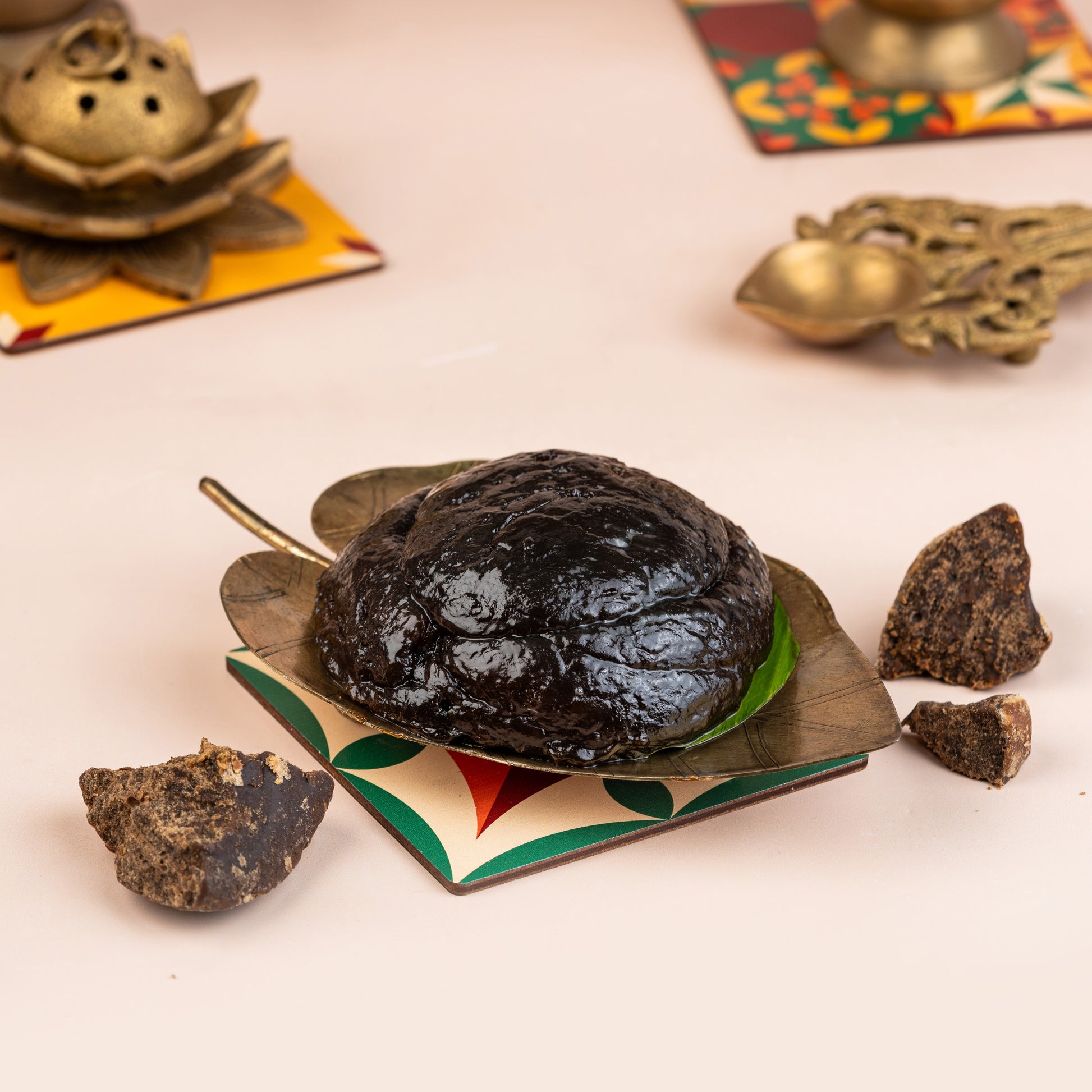 A lump of dark, solid food item on a decorative plate with a piece broken off to the side, presented on a table with floral patterned placemats.