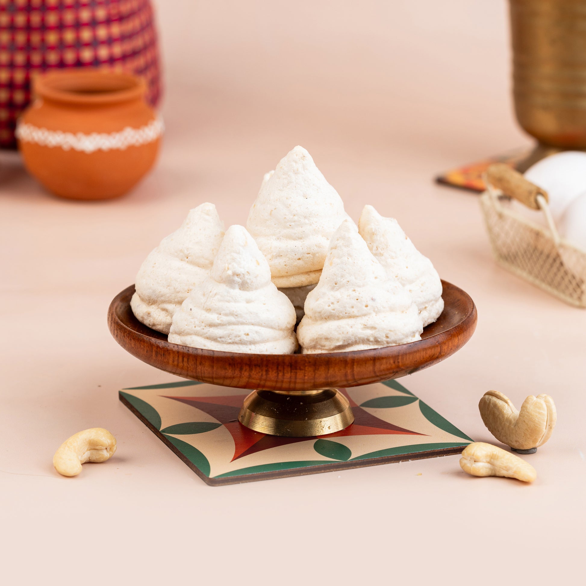 A plate with four macaroon pastries on it, with a small bowl of jam and some nuts beside it.