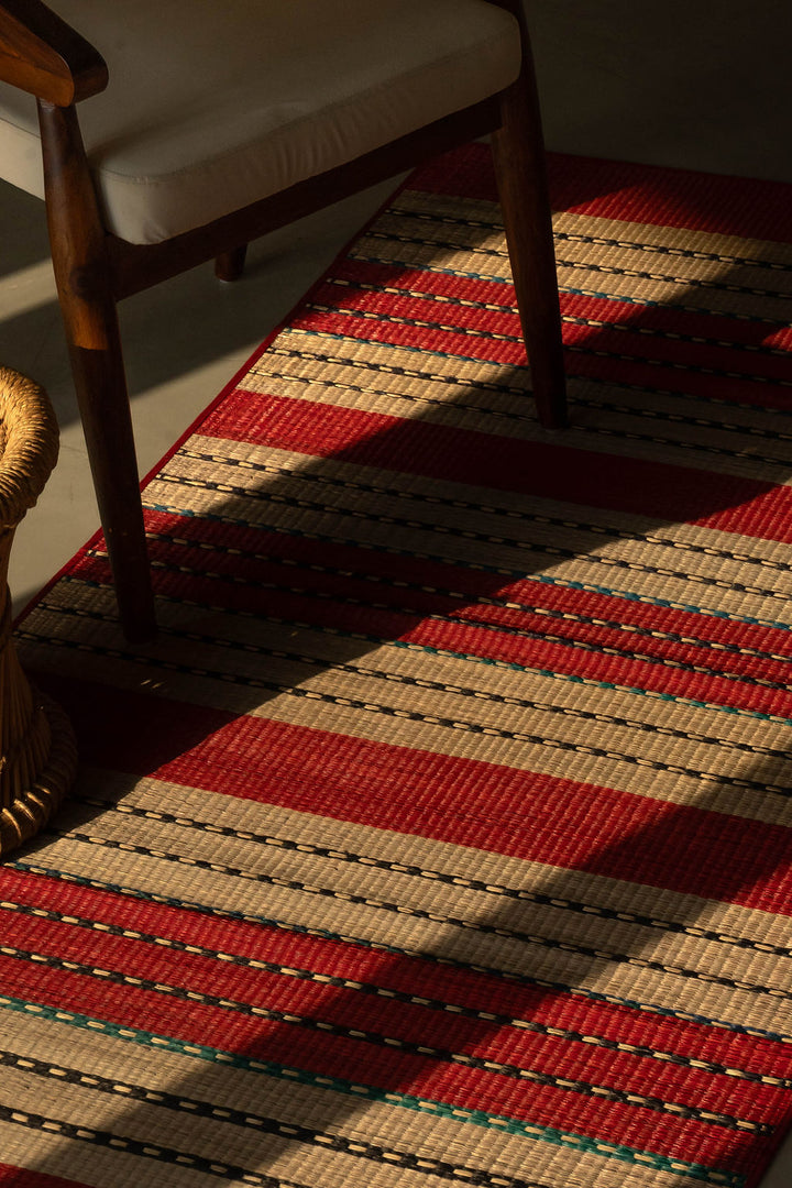 Red and beige striped rug with a wooden chair on a dark floor.
