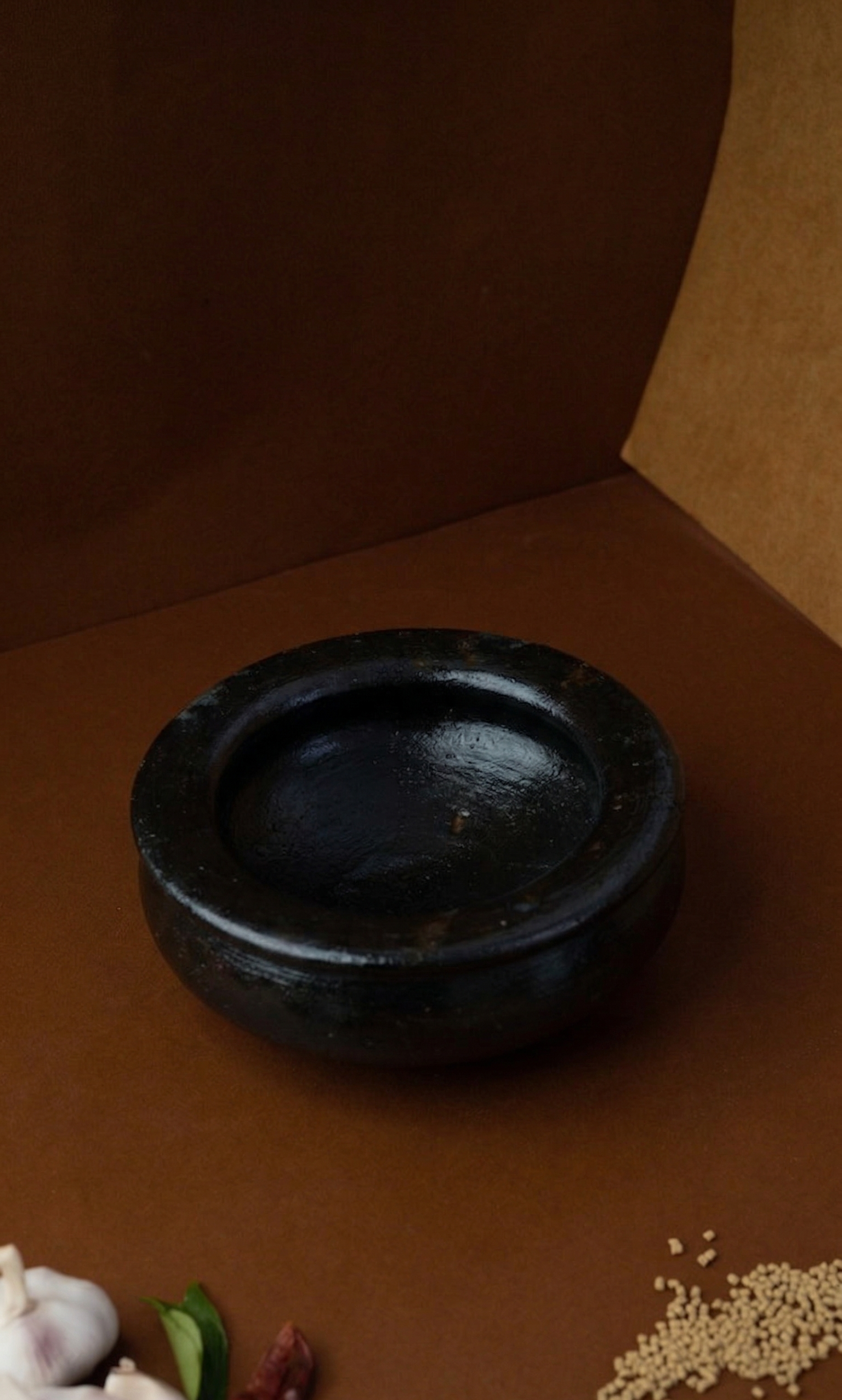 Black Seasoned Uruli Kalchatty on a brown surface with decorative elements.