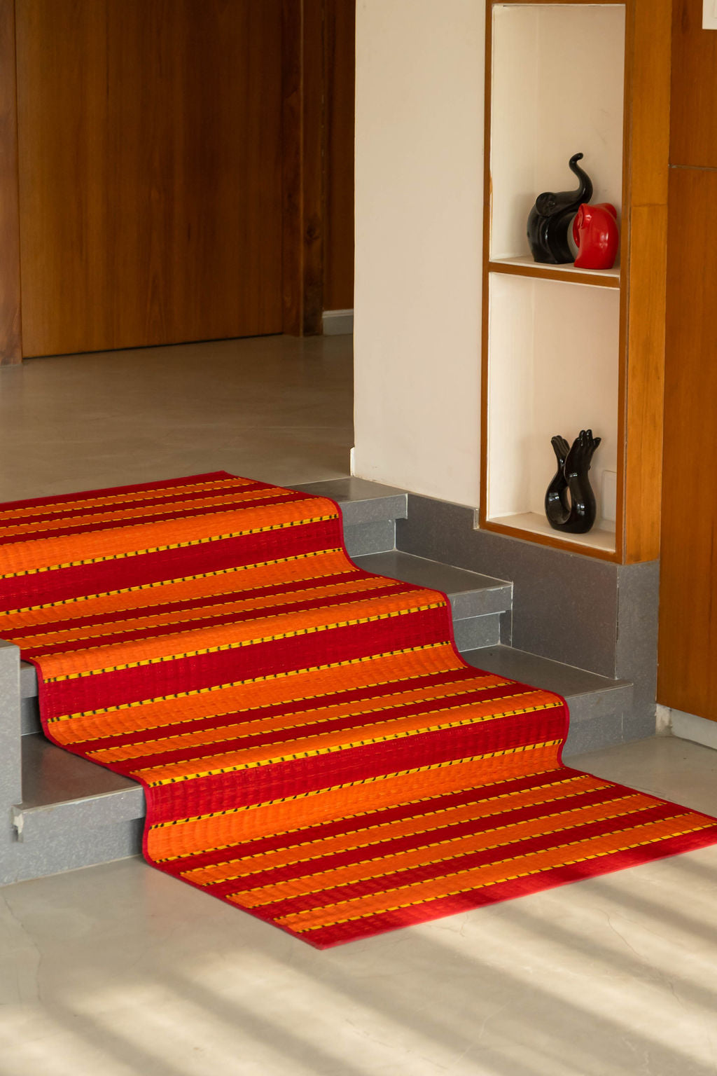 Red and orange striped carpet on a staircase in a home setting.