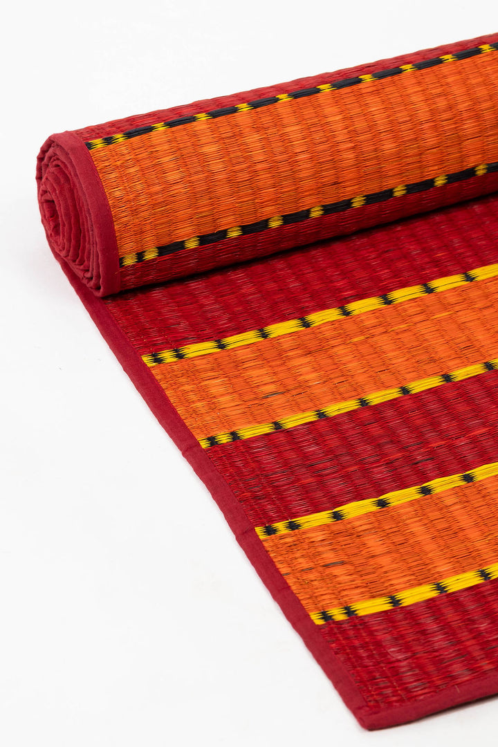 Rolled-up red and orange mat with yellow and black pattern on a white background