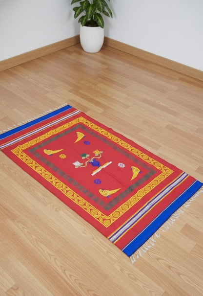 Decorative Pattu Red Jamakkalam with colorful patterns on a wooden floor