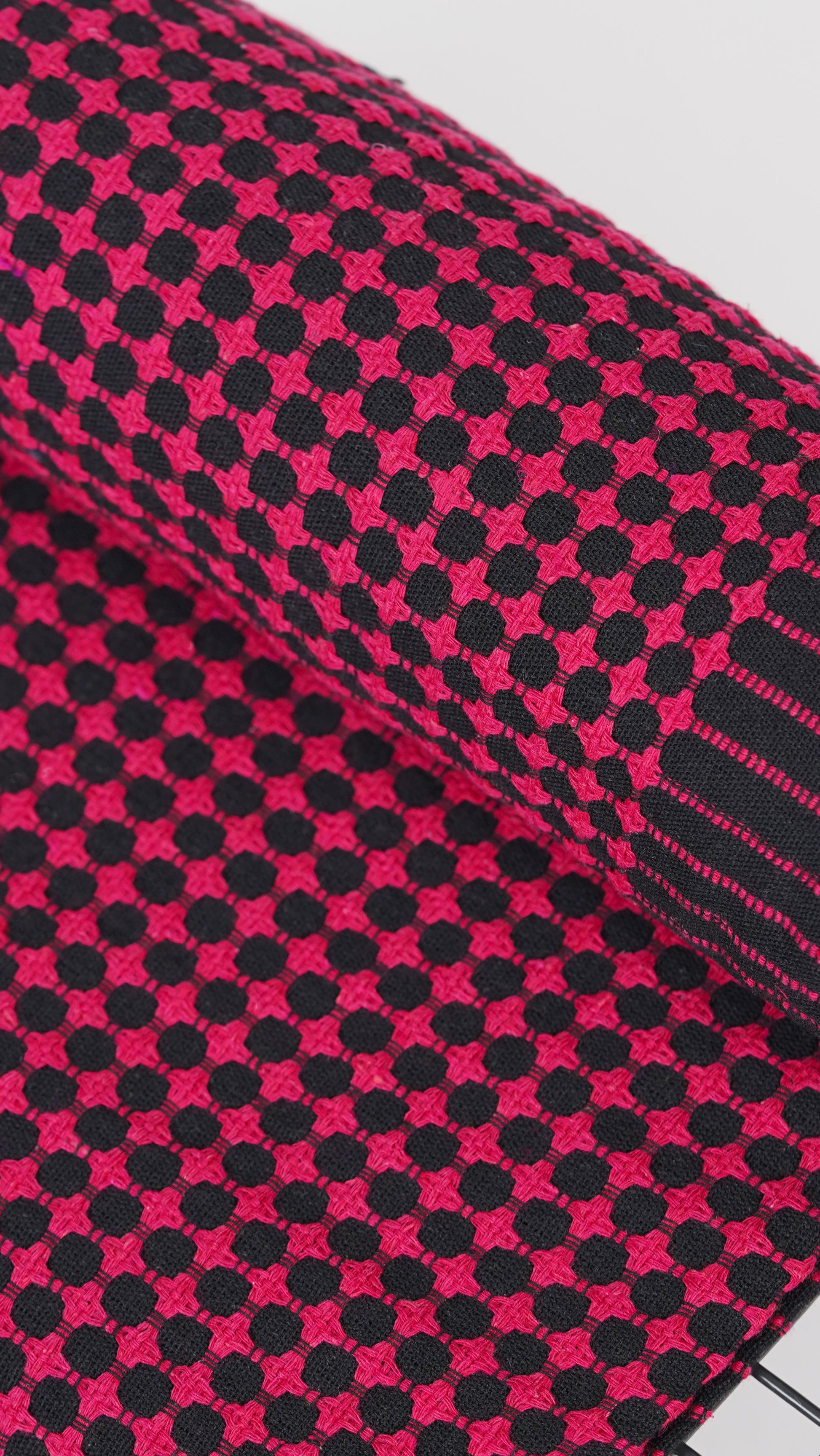 Close-up of a pink and black checkered fabric with a patterned design.